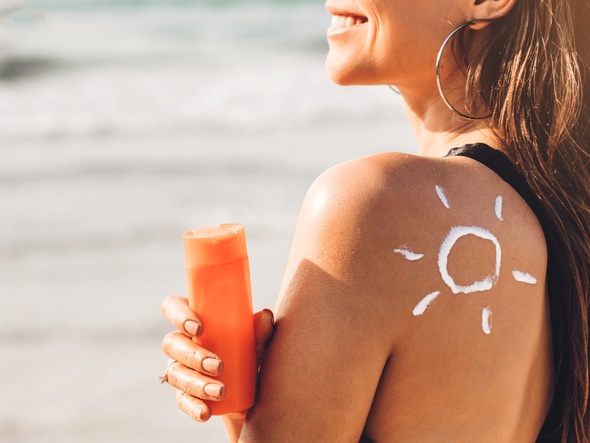 lachende Frau mit Sonnencreme auf der Schulter